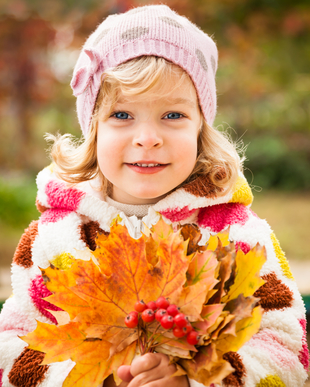 Happy smiling child holding yellow maple leaves in autumn park